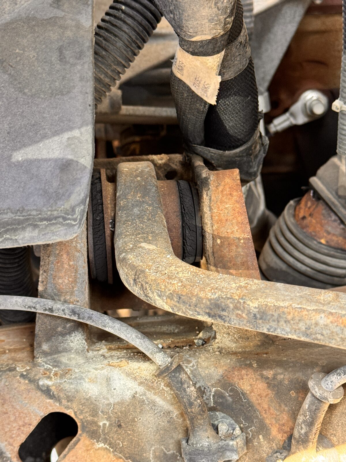 Close inspection of a rusted lower control arm and suspension bushing