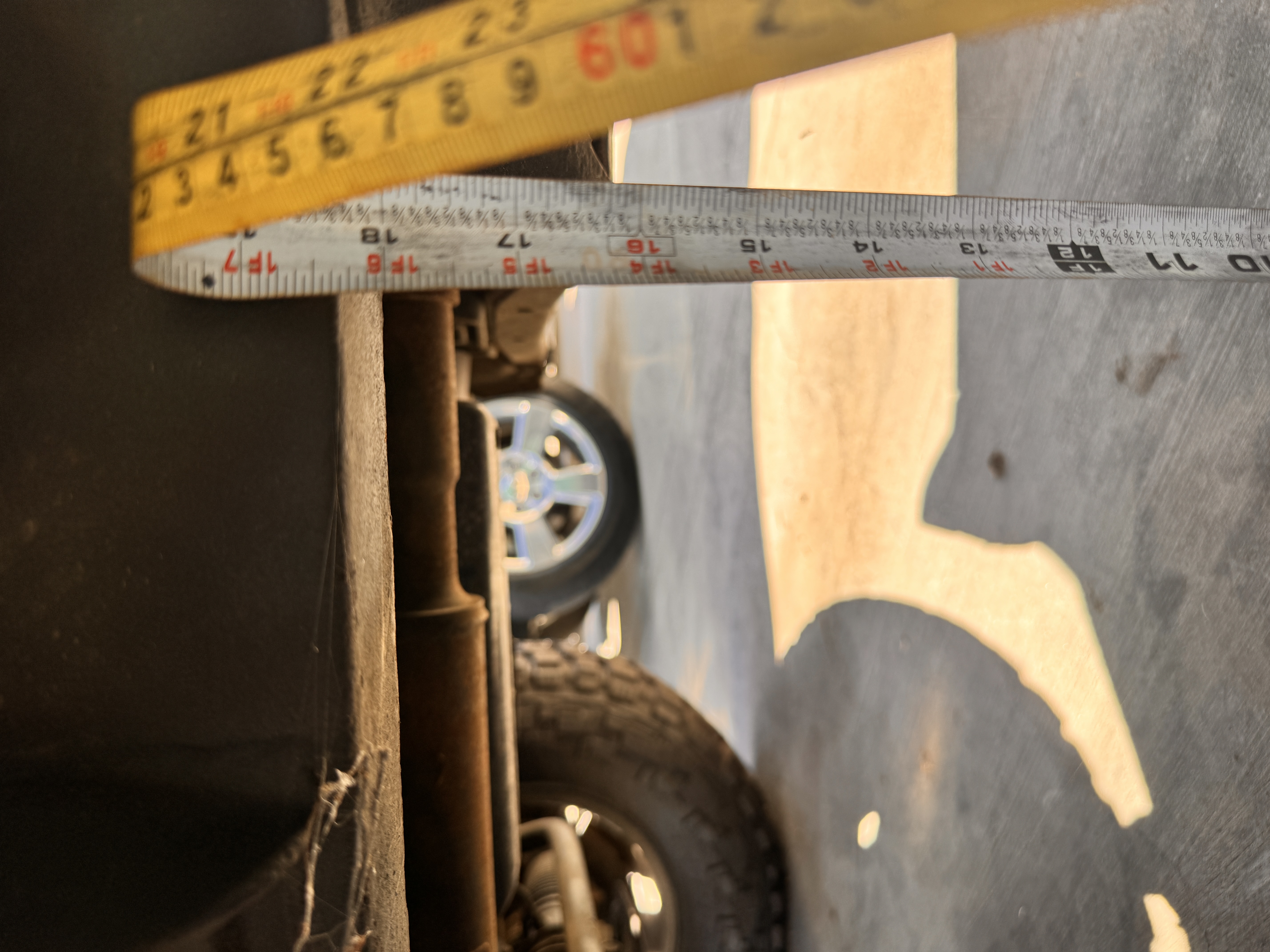 Technician measuring tire and suspension ride height during inspection
